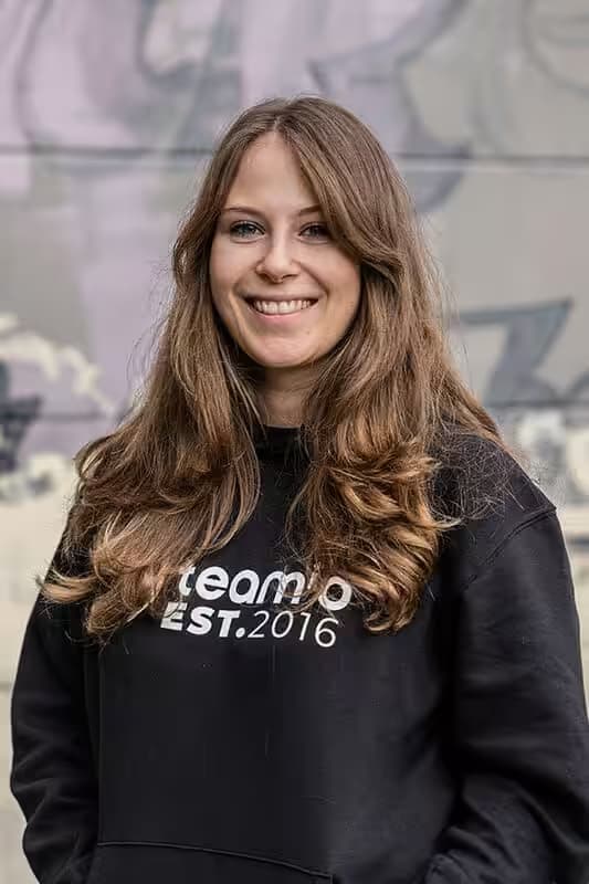 Smiling woman wearing a “teamio” jumper.
