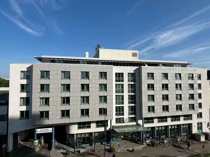 FOUR Essen City Centre - Hotelgebäude mit Tiefgarageneinfahrt, blauer Himmel