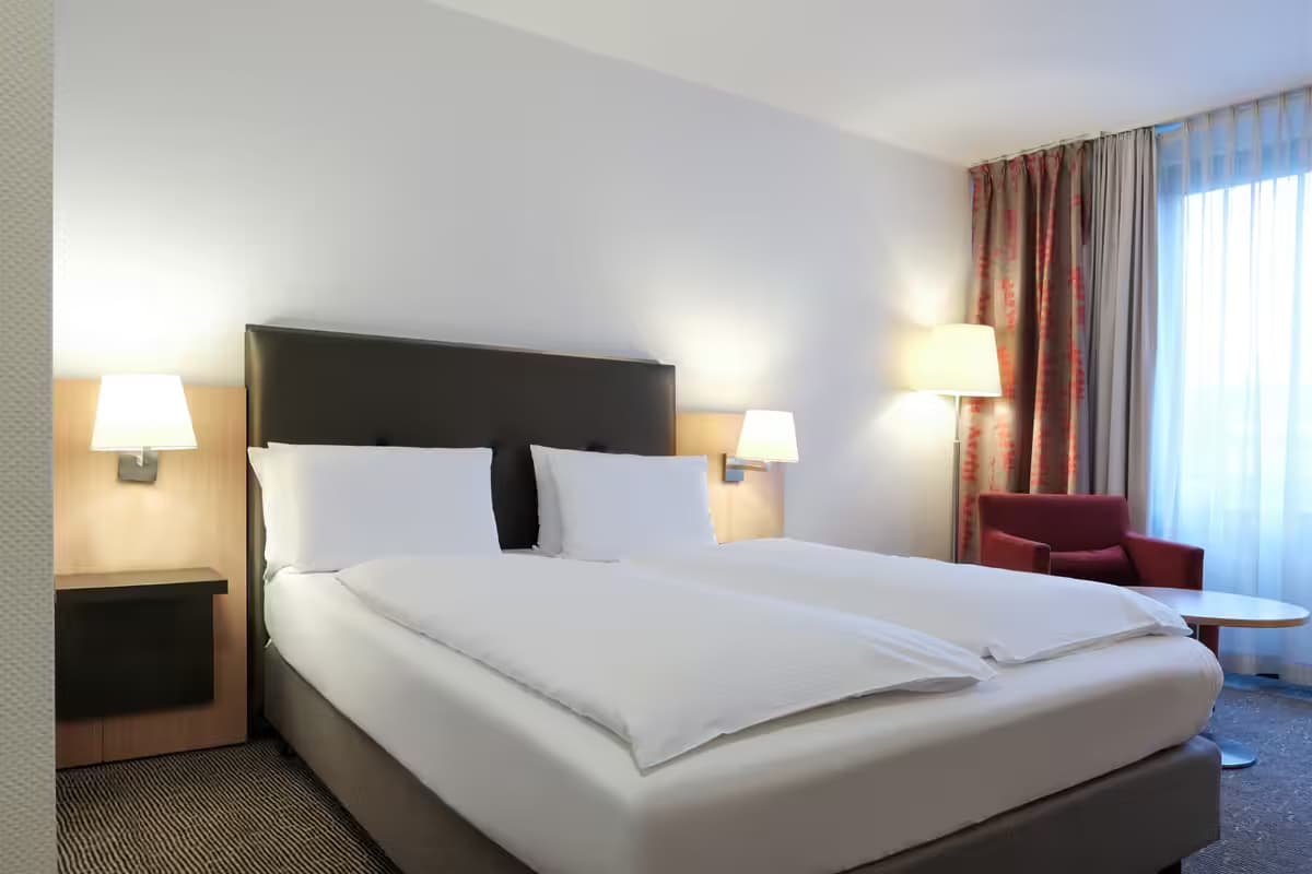 FOUR Essen City Centre - Hotelzimmer mit Doppelbett und Sessel