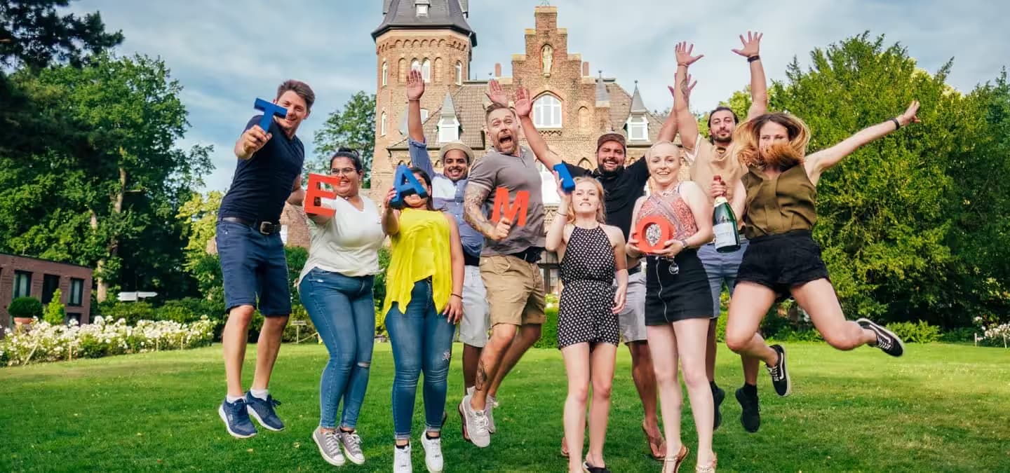 Gruppe springt vor einem Schloss.