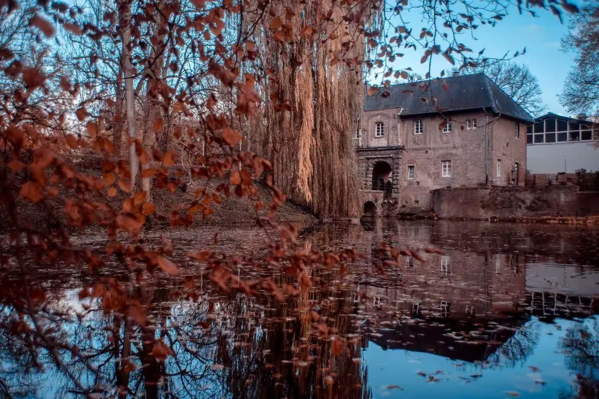 Historisches Gebäude neben Herbstteich in idyllischer Landschaft