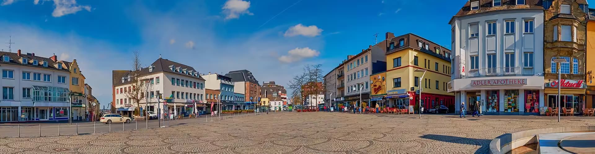 Städtischer Platz mit Geschäften und blauem Himmel.