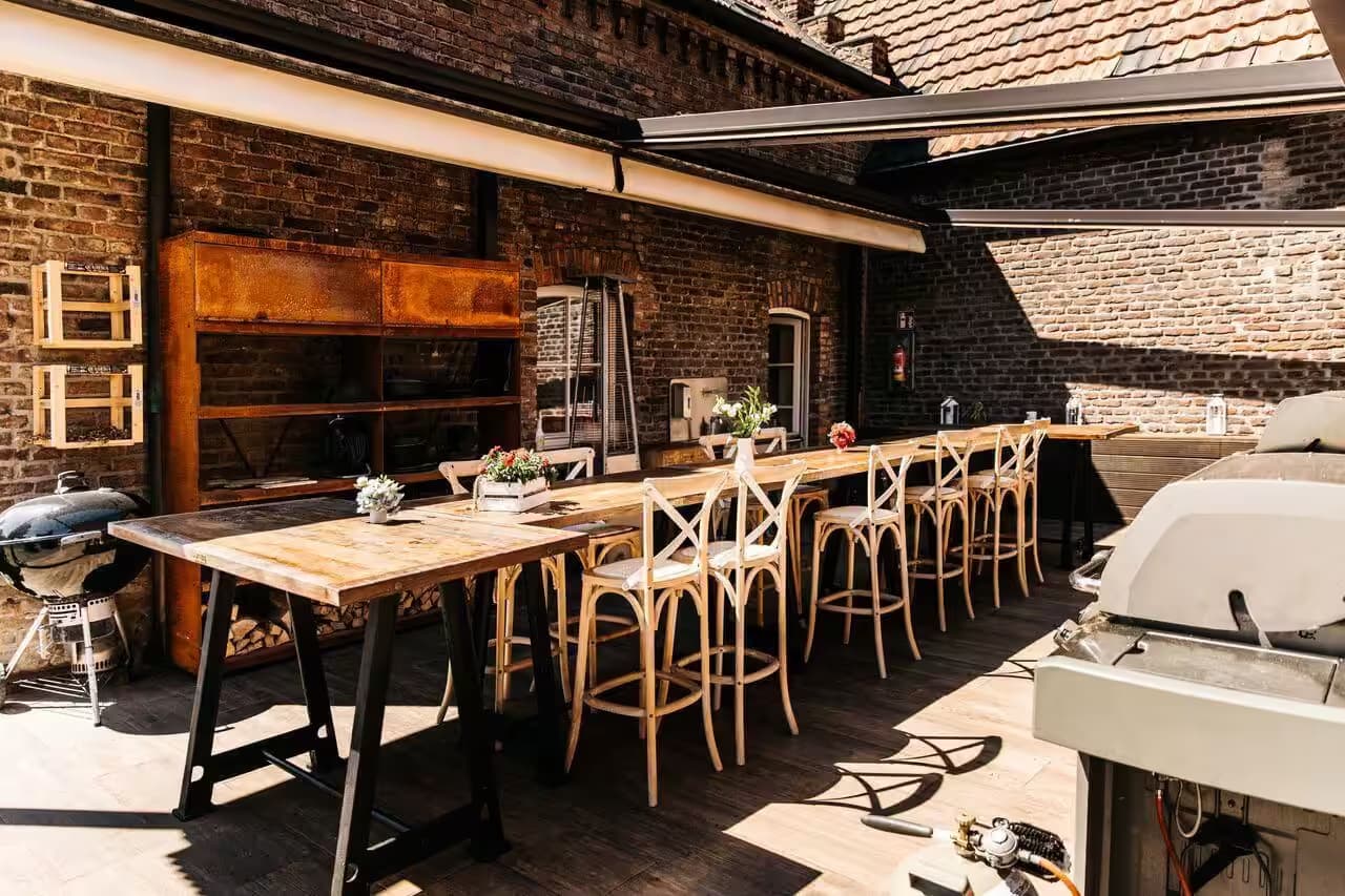 Gemütliche Terrasse mit langem Holztisch und Stühlen.
