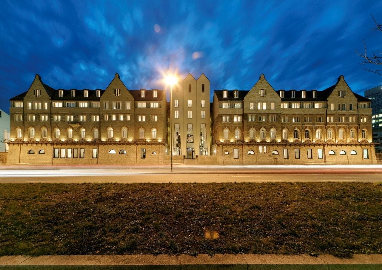 Beleuchtete Fassade des ARCOTEL Camino am Abend