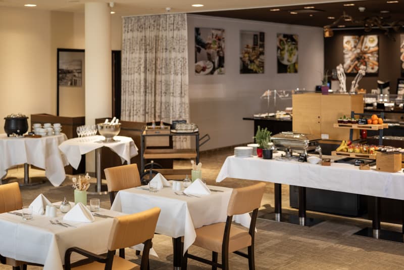 Frühstücksbereich im ARCOTEL Camino mit Buffet und eingedeckten Tischen