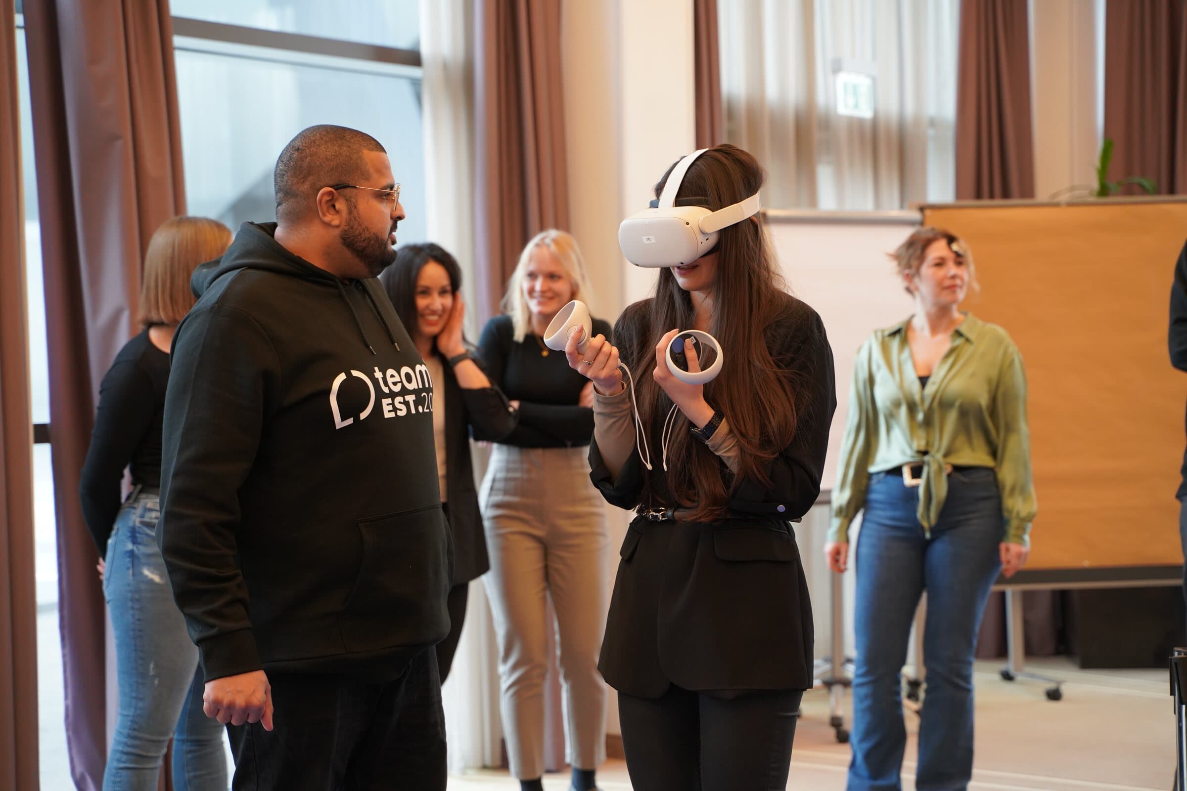 Teilnehmerin mit VR-Brille bei der VR Experience, ein teamio-Betreuer steht daneben