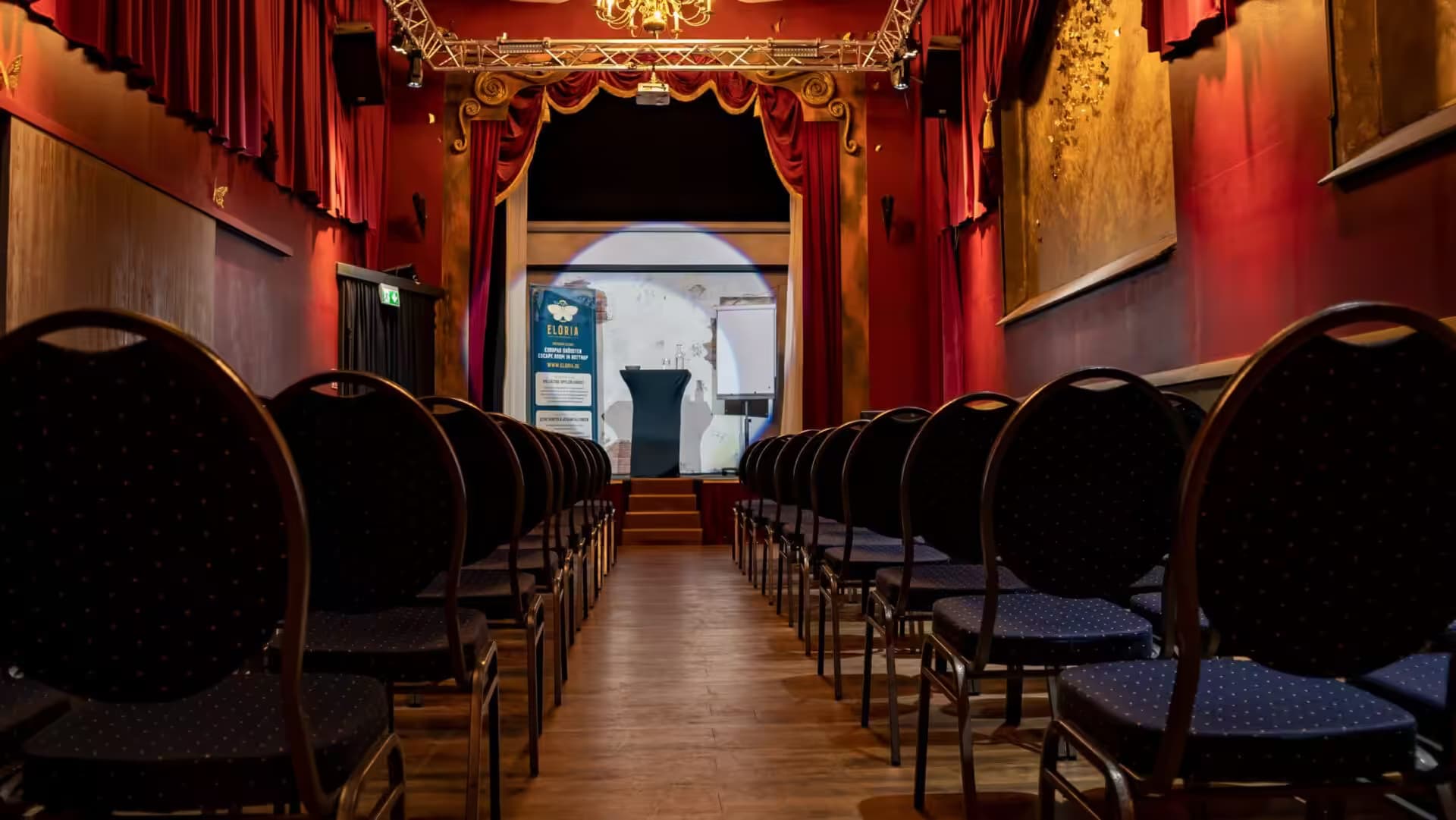Empty theatre with a stage and chairs.