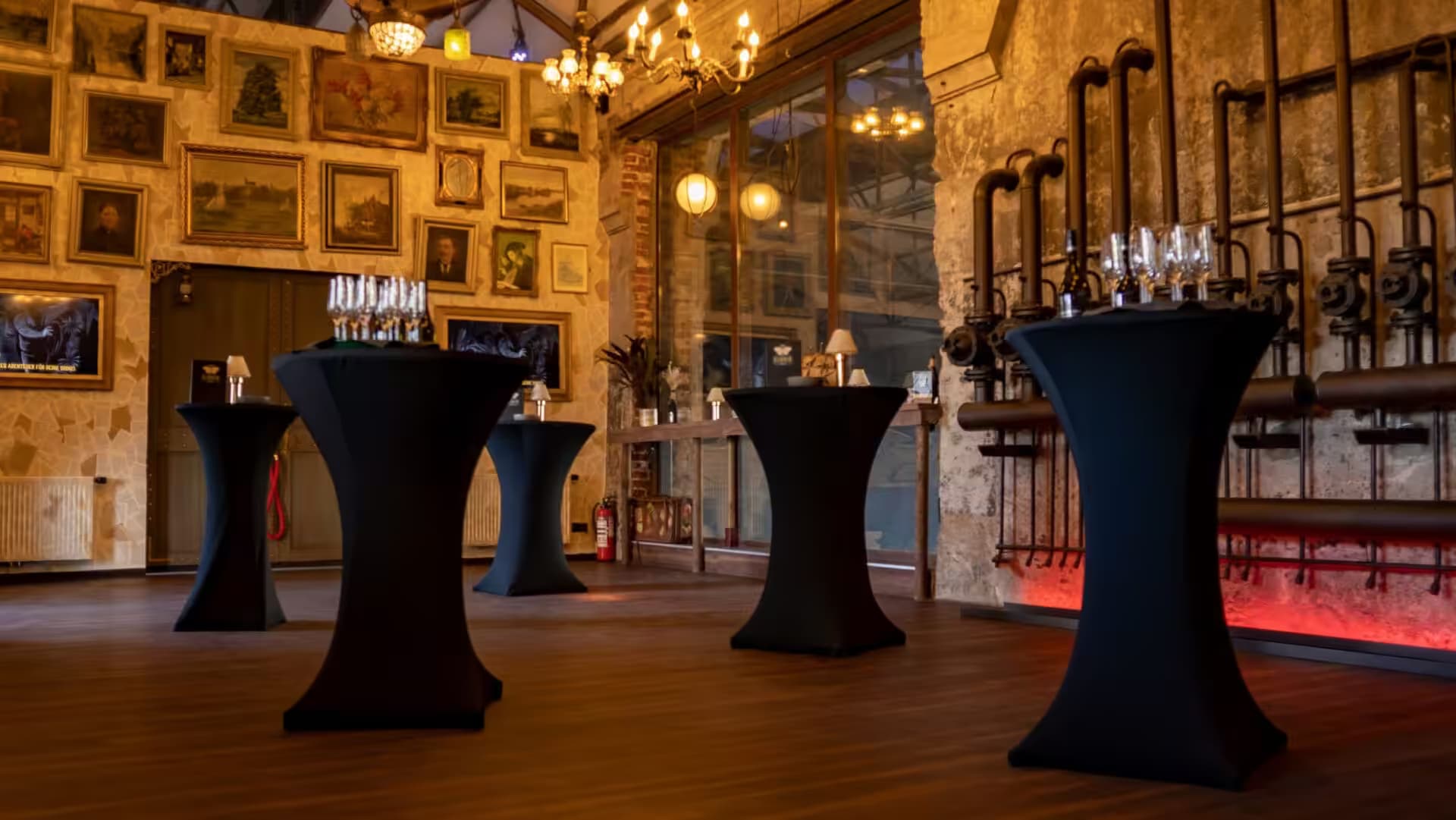 Industrial event space with standing-height tables and artworks.
