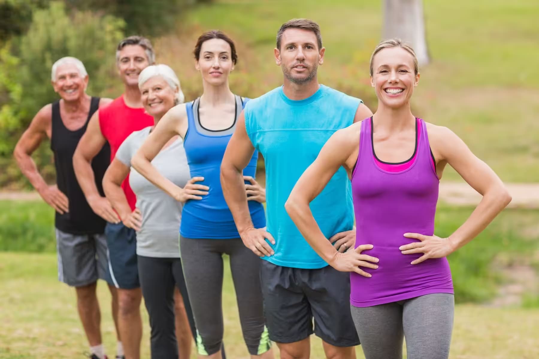 Gruppe beim gemeinsamen Fitnesstraining auf einer Wiese