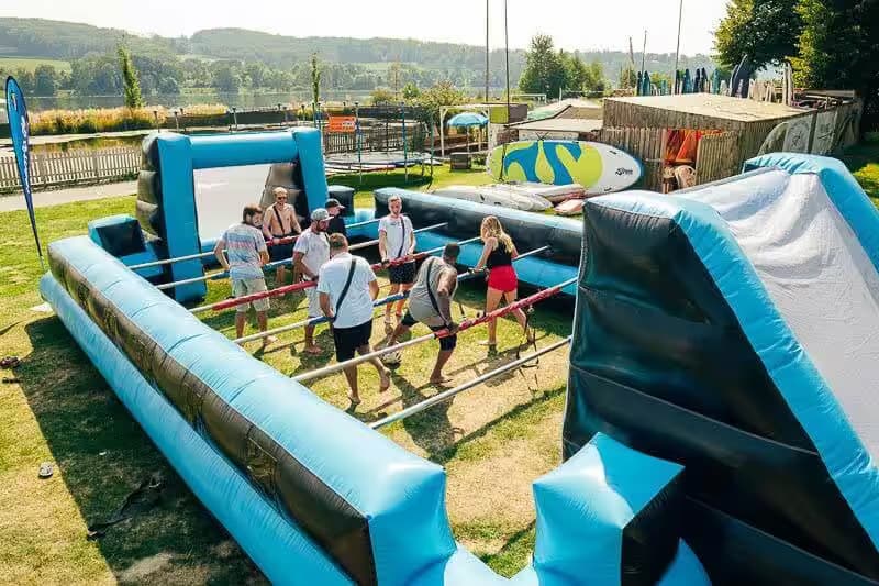 Menschen spielen auf einem aufblasbaren Tischfußballfeld im Freien.