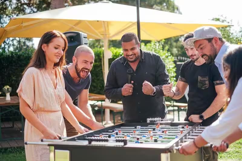 Gruppe spielt Tischfußball im Freien.