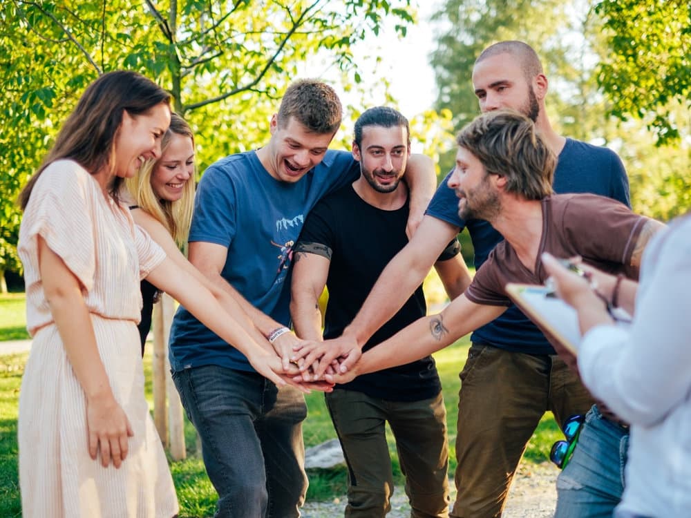 Participants putting their hands together in the centre during a team-building activity