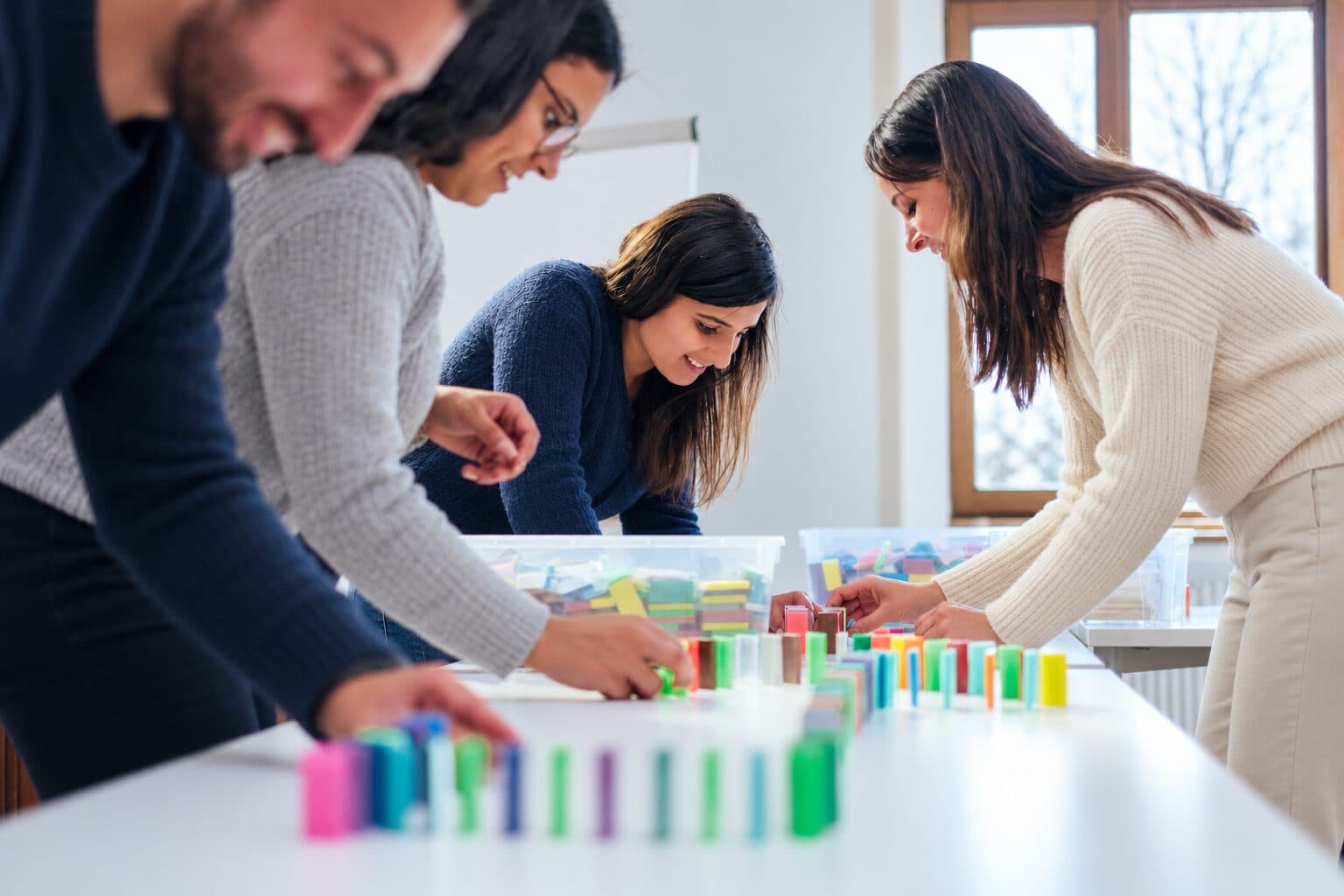Teilnehmende stellen bunte Dominosteine auf einem Tisch auf