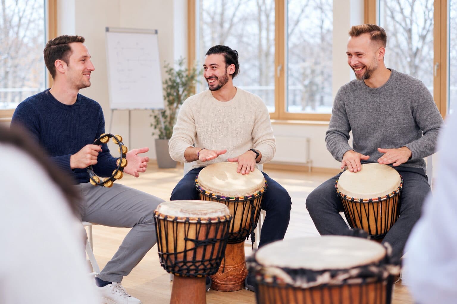 Drei Teilnehmer spielen Djembe und Tamburin