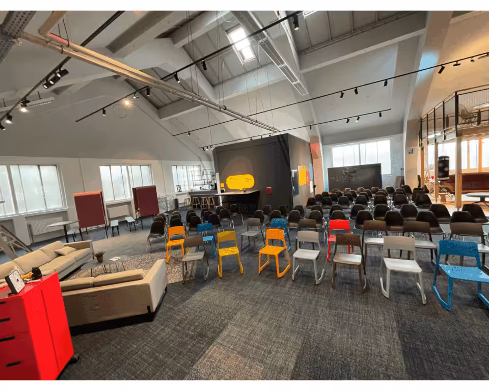 Moderne Mehrzweckhalle mit bunten Stühlen und Bühne.