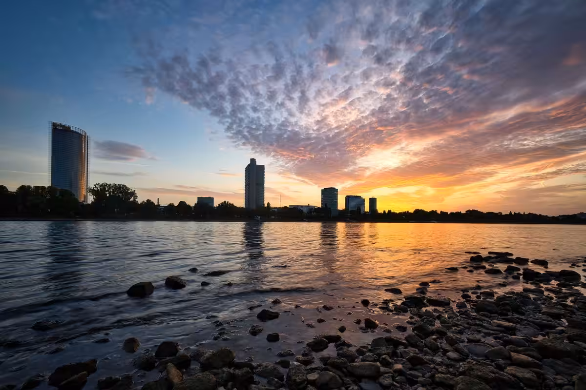 Sonnenuntergang am Fluss in Bonn mit Gebäuden im Hintergrund