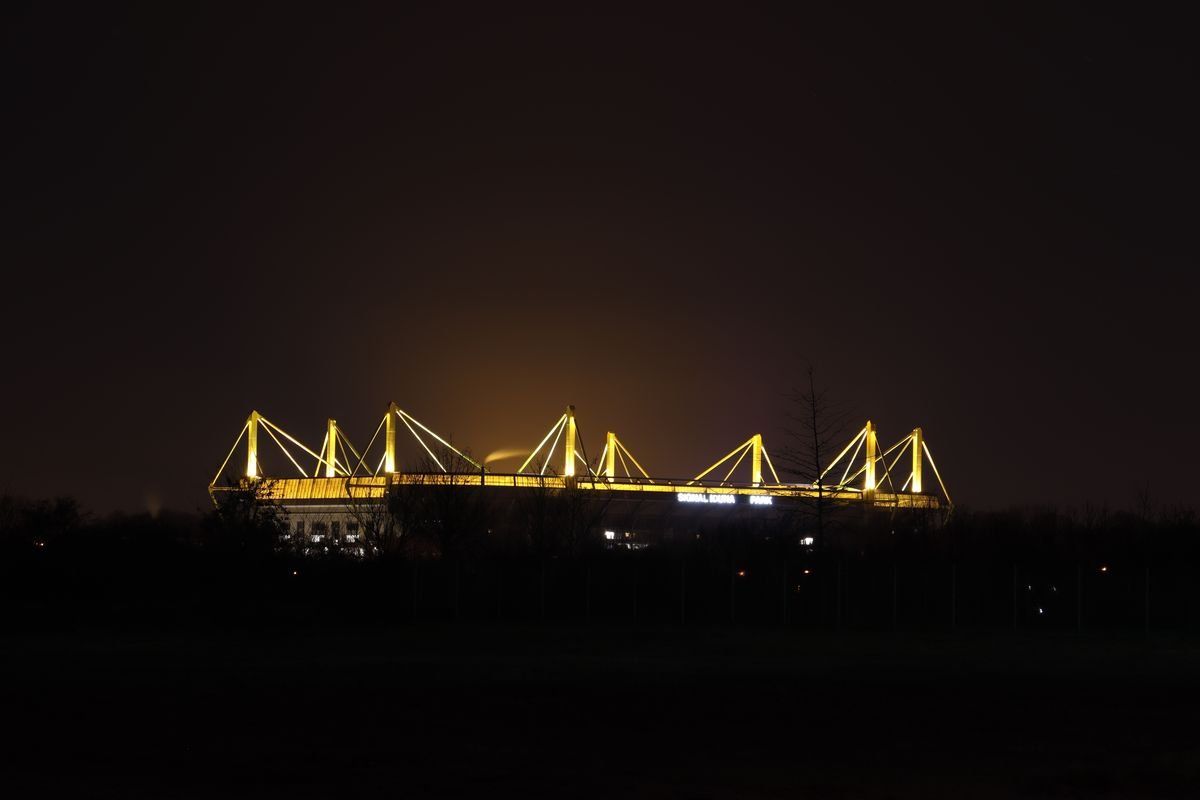 Beleuchtetes Stadion (Signal Iduna Park) bei Nacht mit markanten Gelben Details.