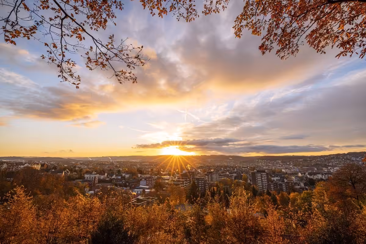 Herbstsonnenuntergang über einer Stadt mit Wolkenbildung.