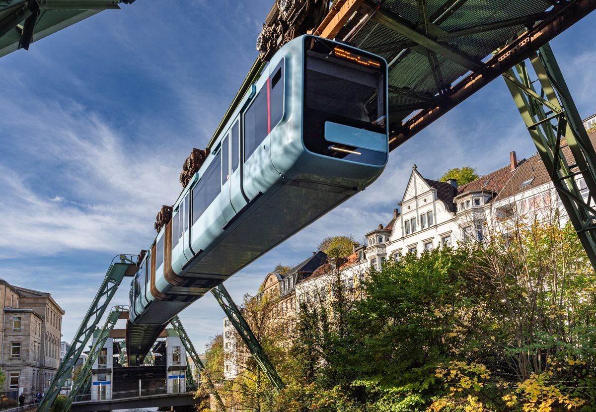 Schwebebahn in Wuppertal fährt über Stadt und Bäume.