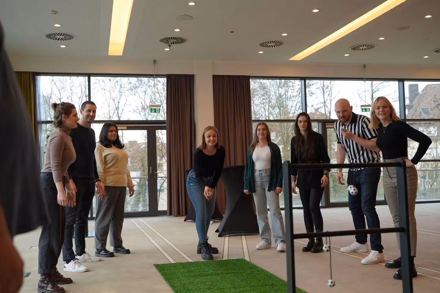 Gruppe spielt im Raum ein Wurfspiel mit Bällen.