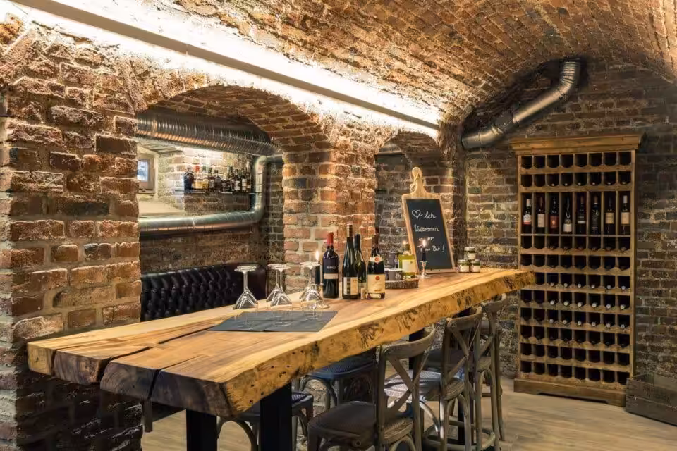 Gemütliche Kellerbar mit Holztisch und Weinauswahl