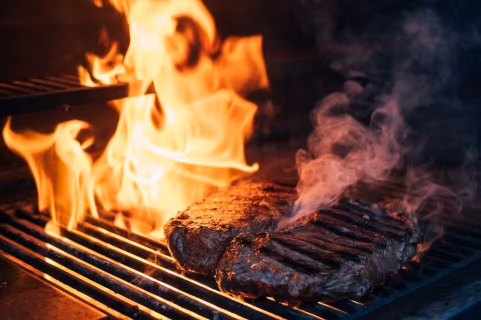 Gegrilltes Steak über offener Flamme auf Grillrost.