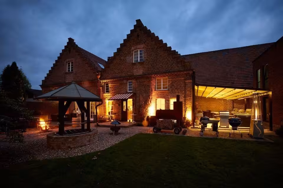 Historisches Haus mit Garten, beleuchtet bei Dämmerung.