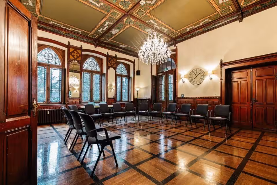 Historischer Raum mit Stühlen, Kronleuchter und Holztäfelung