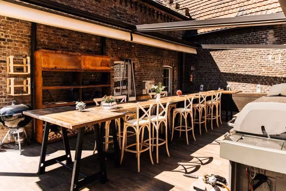 Gemütliche Terrasse mit langem Holztisch und Stühlen.