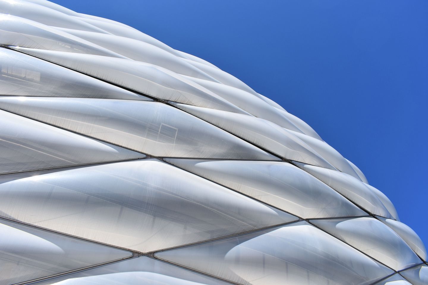 Moderne Stadionarchitektur der Alliianz Arena in München bei blauem Himmel