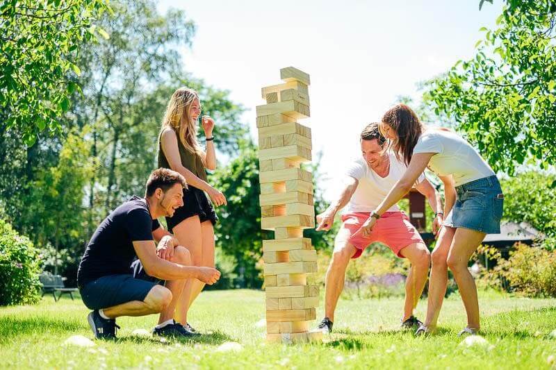 Menschen spielen Jenga im Freien auf Wiese.