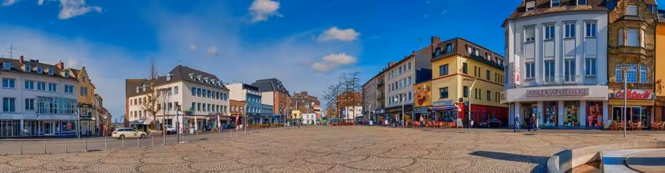 Städtischer Platz mit Geschäften und blauem Himmel.