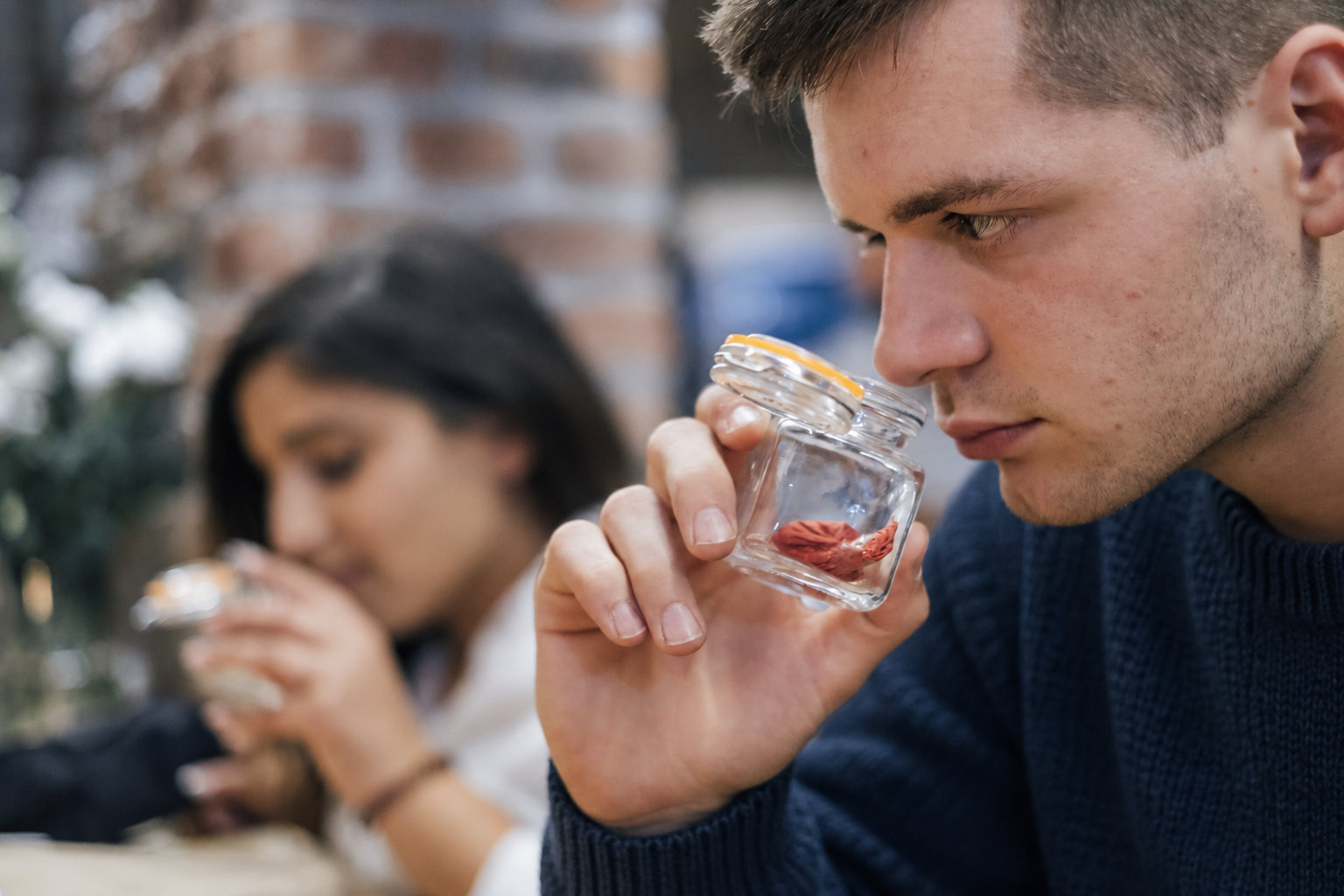 Person prüft den Geruch einer Probe im Glas