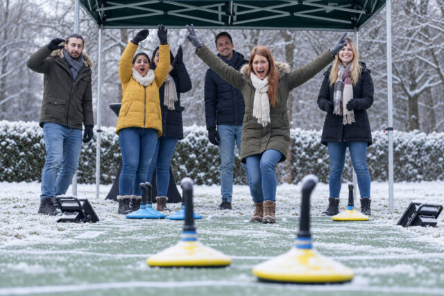Gruppe bei einem winterlichen Teamspiel unter einem Pavillon