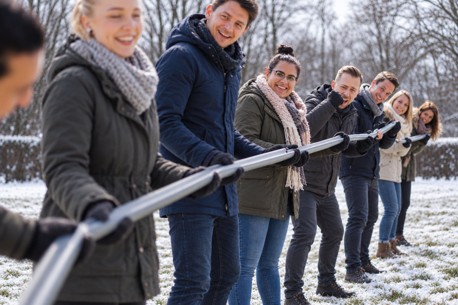 Gruppe löst gemeinsam eine Aufgabe mit Metallstangen im Freien